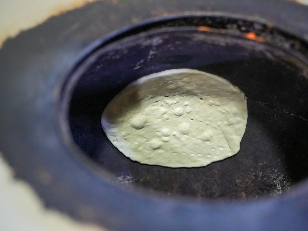 Naan bread baking on the wall of the clay tandoor