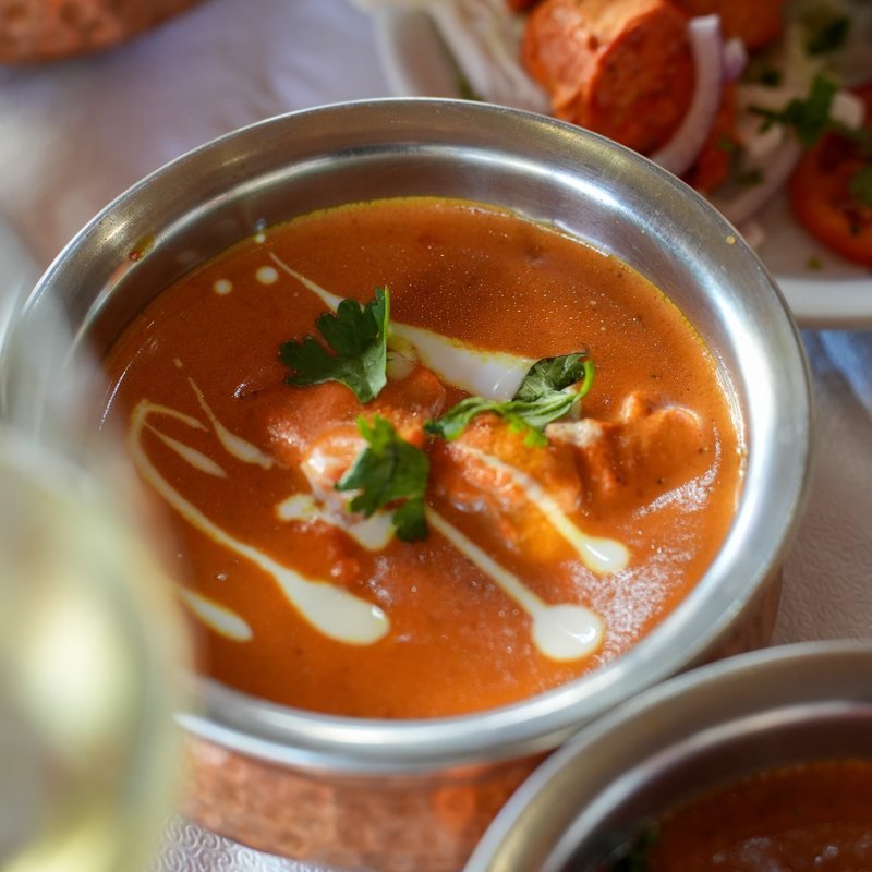 A deep red curry served in a copper bowl