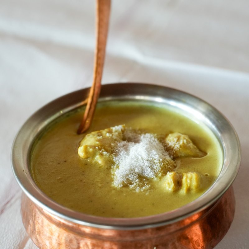 A green spinach-based curry in a copper bowl