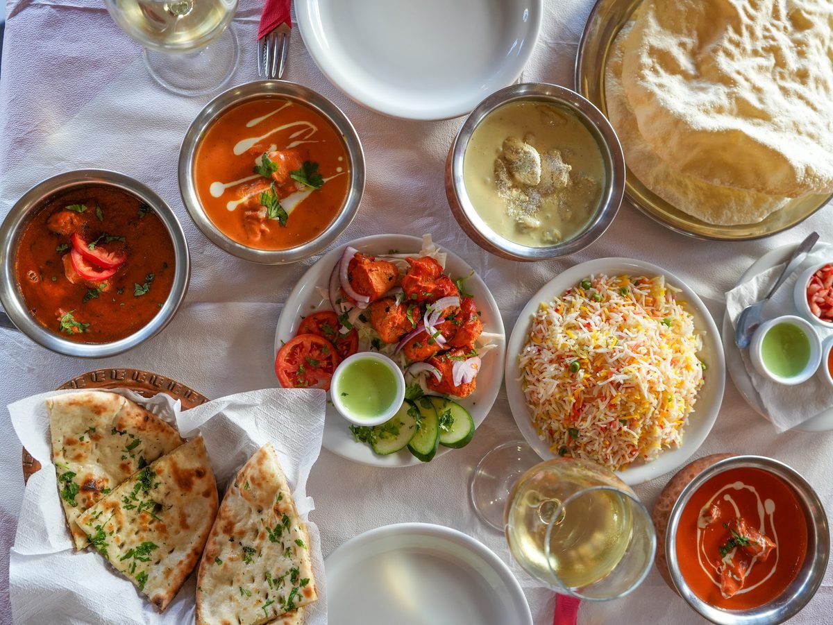 A full table of Indian dishes, naan and wine