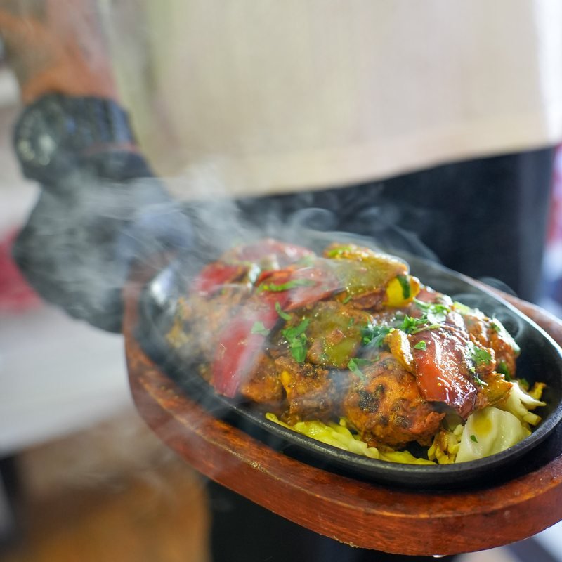 A sizzling tandoori platter arriving at the table