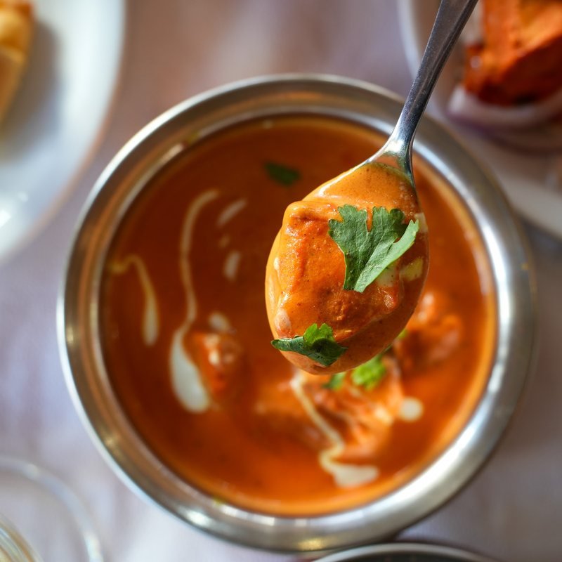 A rich, creamy tomato curry served in a copper bowl