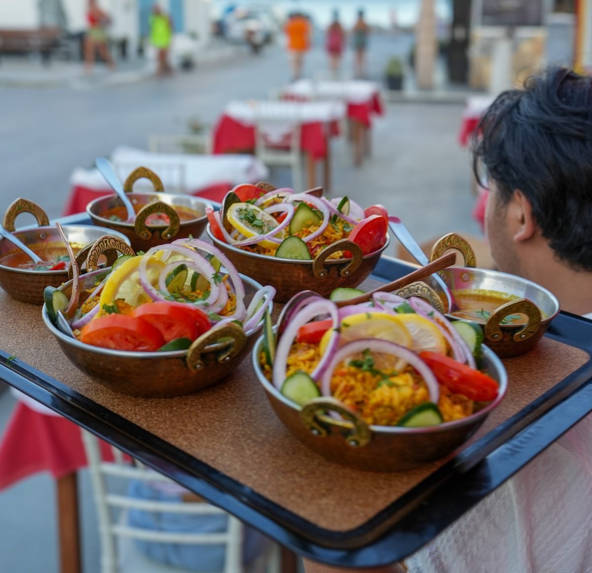 A waiter carrying a tray of biriyani to the table